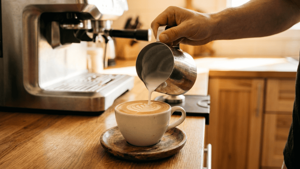 Home espresso machine with flat white being poured in an Australian kitchen.