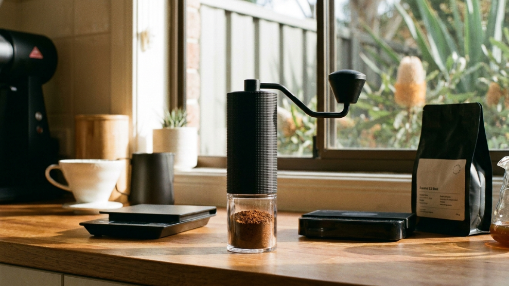 Timemore C3 Pro manual hand grinder in black on an Australian kitchen bench with ground coffee in the catch cup