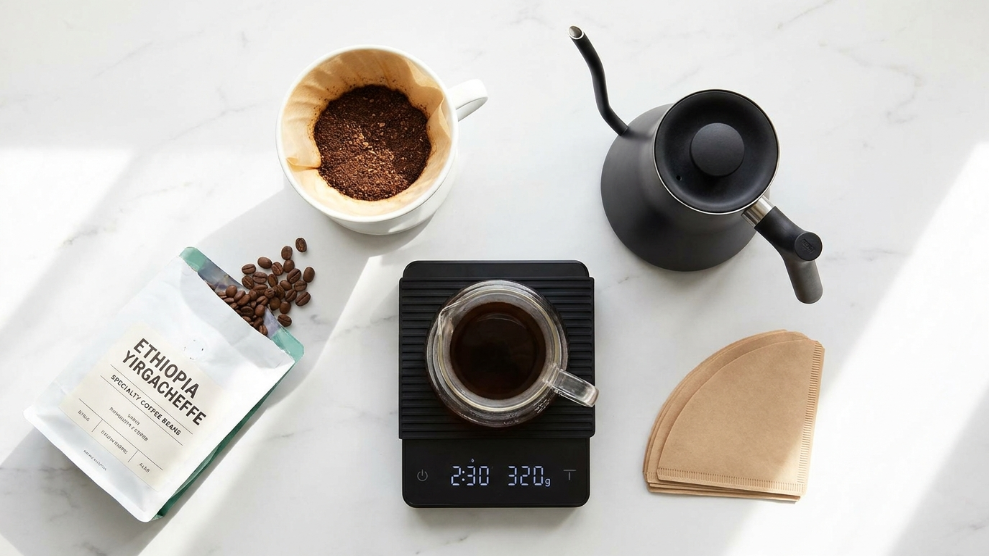 Pour-over coffee equipment lineup including V60 dripper, gooseneck kettle, coffee scale and filters on a kitchen counter