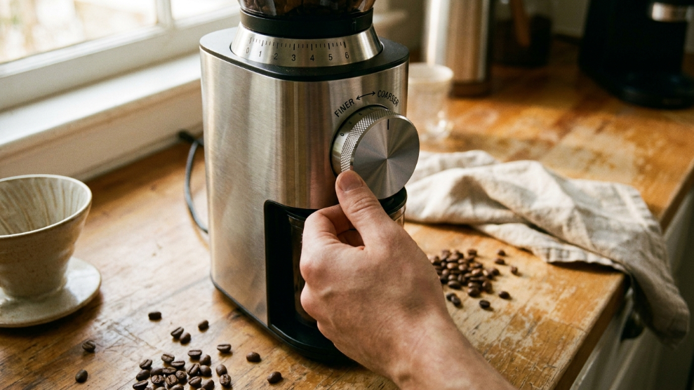Close-up of a coffee grinder dial being adjusted from coarse to finer setting for espresso