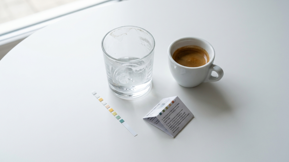 Water testing strip next to an espresso machine showing hard water mineral content affecting extraction.