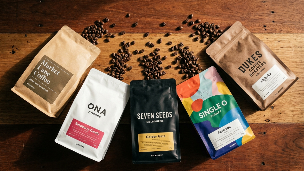 Best coffee beans Australia 2026 showing five specialty coffee bags from Australian roasters fanned out on a timber bench with whole coffee beans
