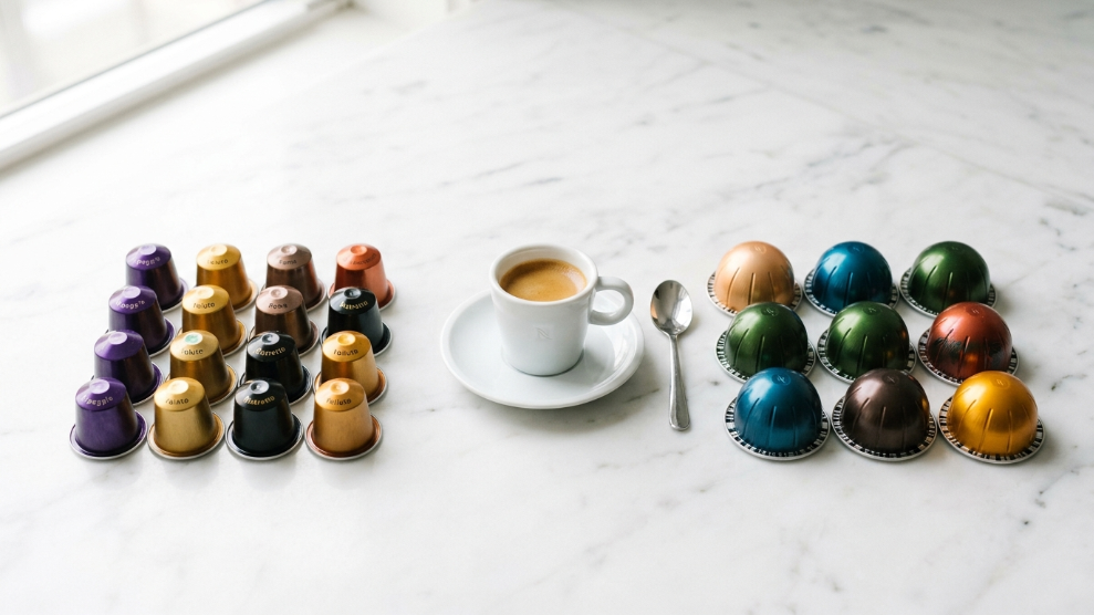 Nespresso Original vs Vertuo comparison 2026 showing Original Line cylindrical capsules and larger dome-shaped Vertuo capsules on white marble with espresso cup